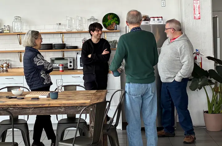 Four team members chat beside the office kitchen counter.