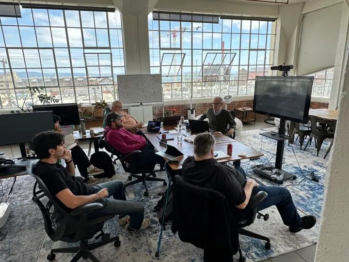 Team members gather around a table for a discussion in the office.