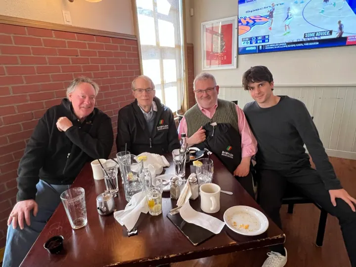 Four team members pose together around a restaurant table.